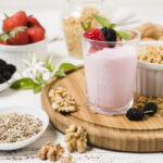 Purple berry oat smoothie in a glass with fresh berries on top