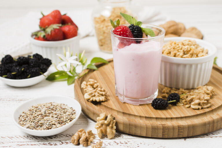 Purple berry oat smoothie in a glass with fresh berries on top