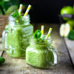 Three green smoothie recipes in glasses with fresh spinach and fruit