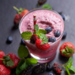 Creamy avocado smoothie in a glass with cacao nibs on top and fresh dates beside it