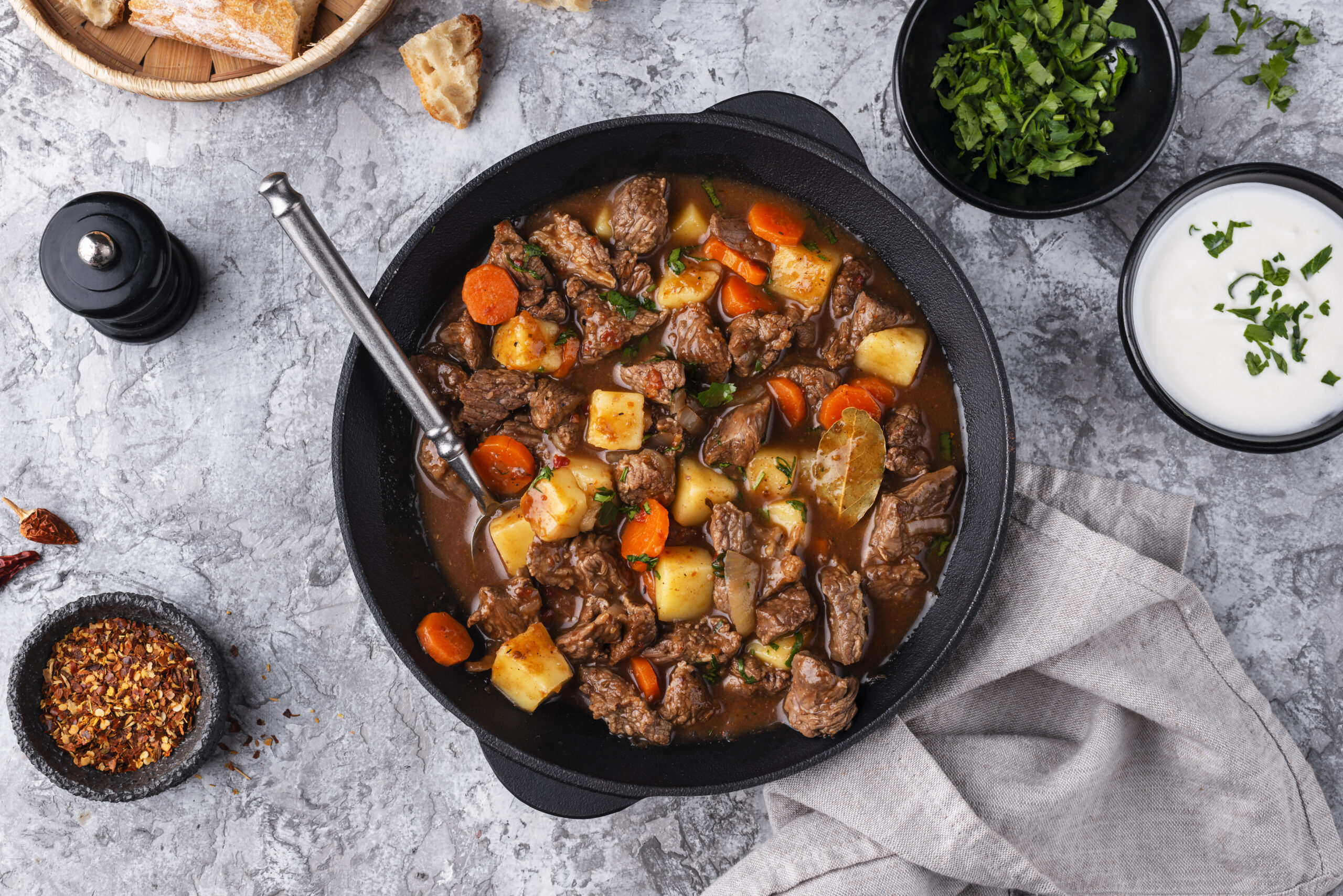 A slow cooker filled with hearty crockpot soup surrounded by fresh ingredients on a wooden table